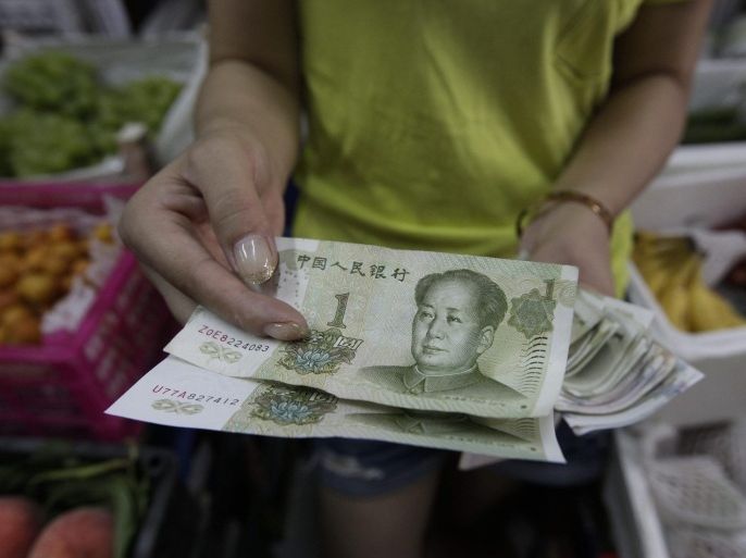 A Chinese fruit vendor shows part of her store earnings in One-Chinese Yuan, or Renminbi, bills in Beijing, China, 11 August 2015. The yuan has sunk to the lowest trading price in a decade after China's central bank devalued the currency on 11 August to aid a slowing economy. The People's Bank of China set the daily mid-point yuan trading price a record 1.9 per cent weaker at 6.2298 to the US dollar.