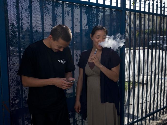 In this Wednesday, July 29, 2015 photo, drug rehab residents, Kevin Lim, left, 18, and Anny Hong, 32, share an electronic cigarette in the parking lot of Nanoom Christian Fellowship in Los Angeles. Nanoom is a church that doubles as a drug rehab for Korean Americans. (AP Photo/Jae C. Hong)