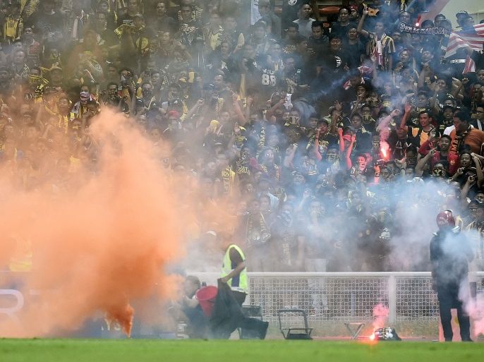 In this picture taken September 8, 2015 Malaysian fans watch after throwing flares on the pitch during the 2018 FIFA World Cup qualifying football match between Malaysia and Saudi Arabia in Shah Alam. Flare-throwing fans forced Malaysia's World Cup qualifier with Saudi Arabia to be abandoned, as they vented their anger over last week's record 10-0 defeat to UAE. AFP PHOTO / MANAN VATSYAYANA