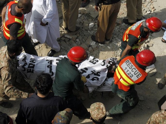 Pakistani rescue workers carry a dead body after recovering it from the rubble at the site of suicide bombing in Shadi Khan, some 80 kilometers (50 miles) northwest from Pakistani capital, Sunday, Aug. 16, 2015. A pair of suicide bombers detonated their explosives at the home of an anti-Taliban provincial minister, killing him and more than a dozen others in eastern Pakistan, officials said. (AP Photo/Anjum Naveed)