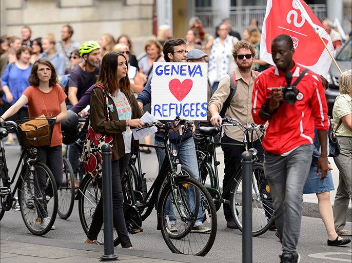 epa04927220 People taking part in a demonstration in support of migrants hold placards with slogans welcoming refugees at the place Neuve, in Geneva, Switzerland, 12 September 2015. EPA
