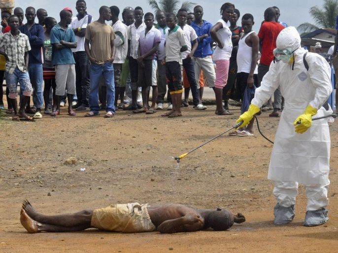 FILE - In this Thursday, Sept. 4, 2014 file photo, a health worker sprays the body of a man suspected of dying from Ebola with disinfectant chemicals in Monrovia, Liberia. In the fall of 2014 when Martin Meltzer of the Centers for Disease Control and Prevention calculated that 1.4 million people might contract Ebola in West Africa, the world paid attention. This was, he said, a worst-case scenario. His estimate was promoted at high-level international meetings. It rallied nations to step up their efforts to fight the disease. But the estimate proved to be 65 times worse than what ended up happening. He dismisses his peers' more complicated calculations as out of touch with political necessities. (AP Photo/Abbas Dulleh)