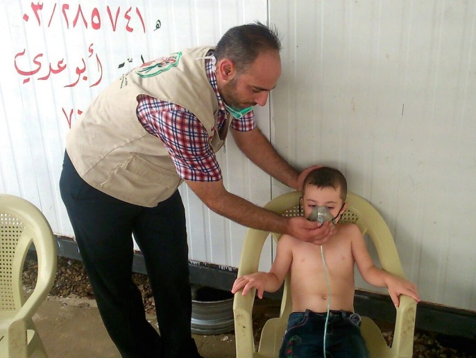 ‪العكاري يسعف أحد الأطفال في مخيم إنماء عكار‬ (الجزيرة)