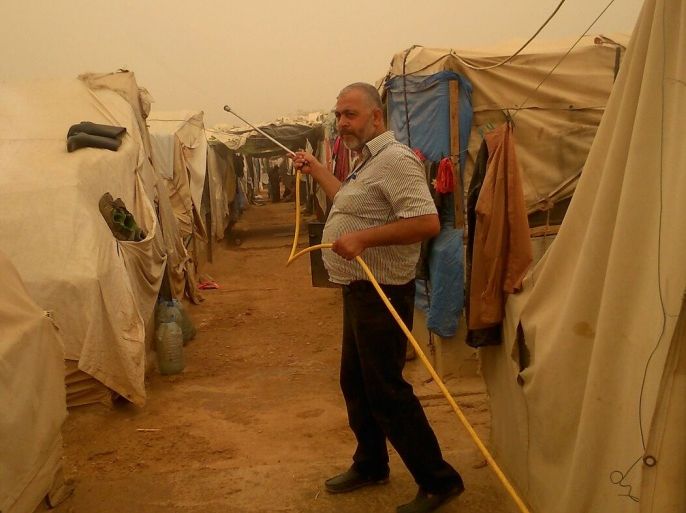 مشرف من إتحاد الجمعيات الاغاثية في مخيم إنماء عكار يرش المياه على الخيام – المحمرة - عكار