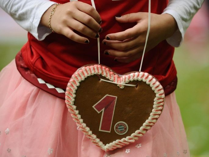 A player's daughter holds a gingerbread heart decorated with Bayern Munich's logo and number 1 as they celebrate winning their 25th Bundesliga title after German first division Bundesliga football match FC Bayern Munich vs 1 FSV Mainz 05 at the Allianz Arena in Munich, southern Germany on May 23, 2015. AFP PHOTO / PHILIPP GUELLANDRESTRICTIONS - DFL RULES TO LIMIT THE ONLINE USAGE DURING MATCH TIME TO 15 PICTURES PER MATCH. IMAGE SEQUENCES TO SIMULATE VIDEO IS NOT ALLOWED AT ANY TIME. FOR FURTHER QUERIES PLEASE CONTACT DFL DIRECTLY AT + 49 69 650050.