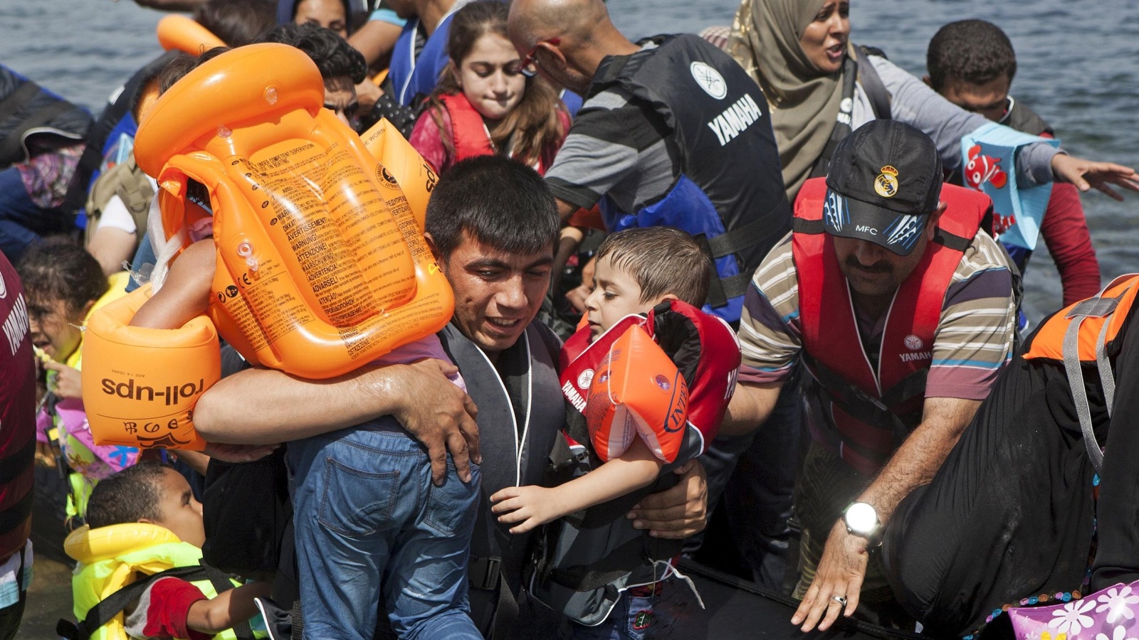 لاجئون سوريون ومنهم أطفال أثناء وصولهم إلى جزيرة ليسبوس (رويترز)