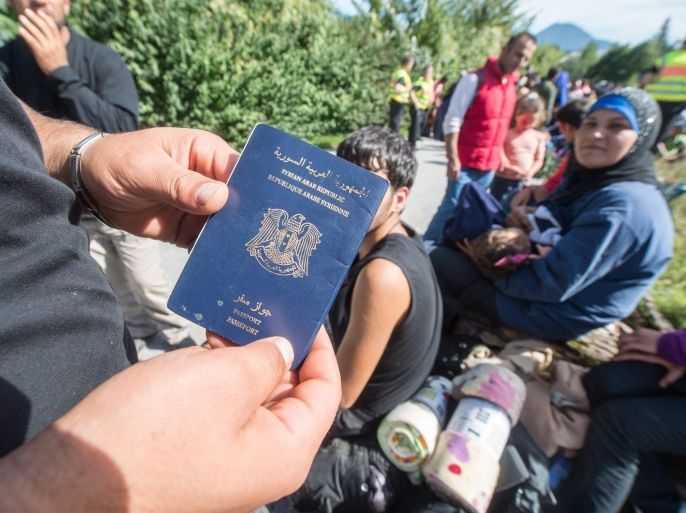 A refugee presents a Syrian passport as is is waiting to cross the German-Austrian border between Salzburg, Austria and Freilassing, Germany, 16 September 2015. Germany imposed immediate emergency border controls with Austria to stem the tide of refugees, the interior minister said 13 September.
