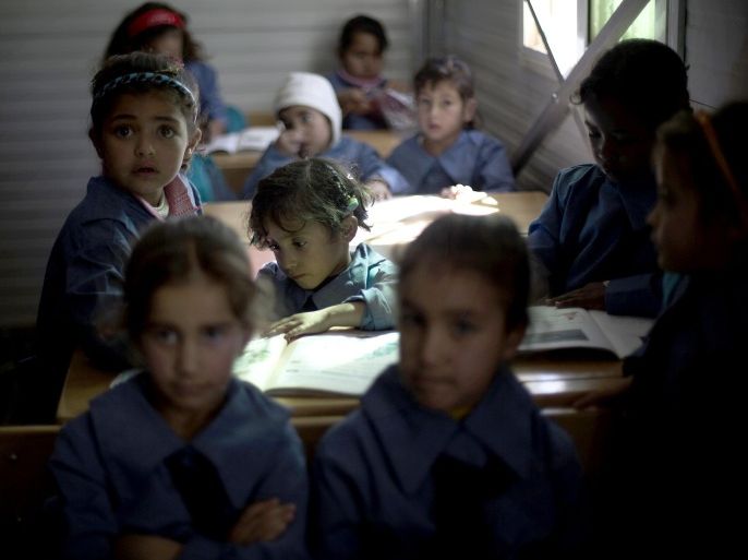 In this Thursday, Oct. 24, 2013 photo, a Syrian girl does schoolwork at a UNHCR school at the Zaatari refugee camp near the Syrian border in Jordan. The camp has three schools, two hospitals and a maternity clinic. (AP Photo/Manu Brabo)