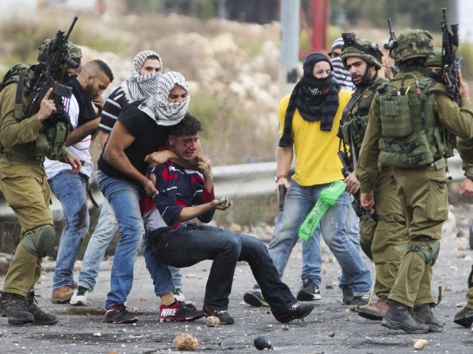 Undercover Israeli police officers and Israeli soldiers detain a wounded Palestinian demonstrator, being pulled up, during clashes near Ramallah, West Bank, Wednesday, Oct. 7, 2015. Palestinian attackers stabbed Israelis in Jerusalem and southern Israel while Israeli troops clashed with Palestinian protesters in the West Bank on Wednesday as Israel's president sought to calm tensions, insisting there will be no changes at a contested Jerusalem holy site that is at the heart of the latest escalation. (AP Photo/Majdi Mohammed)