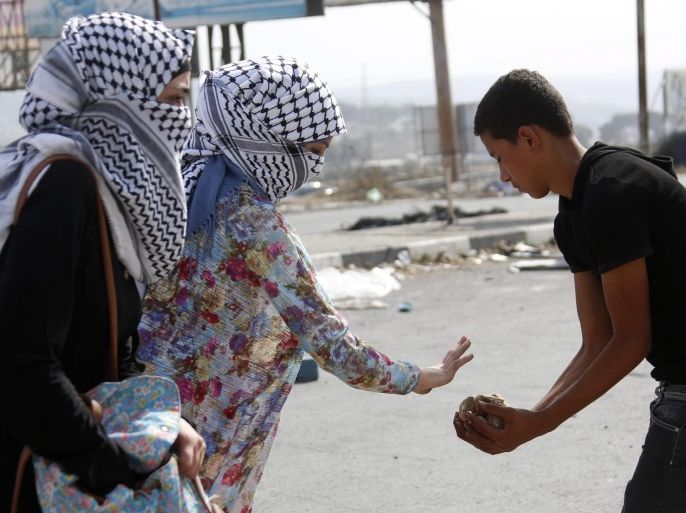 Masked Palestinian girls give stones to protesters during clashes at Howara checkpoint near the West Bank city of Nablus, 12 October 2015. A Palestinian was shot dead in the Old City of Jerusalem n 12 October after trying to stab Israeli border policemen in the Old City of Jerusalem. The death brought to 13 the number of Palestinians from the West Bank killed in an outburst of violence since 01 October, the ministry said. At least half of them were shot dead after or during attempts to stab Israeli bystanders. Four Israelis have been stabbed to death.