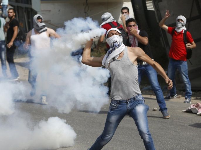 A masked Palestinian protester hurls back a tear gas canister fired by Israeli troops during clashes in the West Bank city of Hebron October 18, 2015. Forty-one Palestinians and seven Israelis have died in recent street violence, which was in part triggered by Palestinians' anger over what they see as increased Jewish encroachment on Jerusalem's al-Aqsa mosque compound. REUTERS/Mussa Qawasma