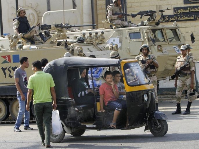 Egyptians drive their traditional tok-tok in front of armored vehicles guarding Torah Prison, where ousted President Hosni Mubarak is held in Cairo, Egypt, Wednesday, Aug. 21, 2013. An Egyptian court ordered Wednesday the release of ousted President Hosni Mubarak, but it is not yet clear if the ailing ex-leader will walk free after over two years in detention, officials said. The prospects of Mubarak’s release after the 2011 uprising against him, and a slew of court cases that made him the first Arab leader to be tried by his own people, are likely to further fuel the rest that has hit Egypt following the military coup against his successor, the first freely elected president Islamist Mohammed Morsi. (AP Photo/Amr Nabil)