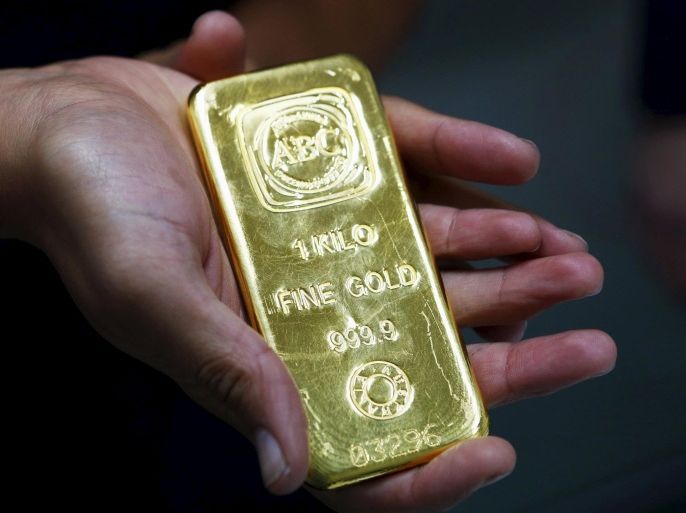 A woman holds a one-kilogram gold bar at the headquarters of the Australian Bullion Company (ABC) in Sydney in this April 19, 2013 file photo. Gold stabilised on July 21, 2015 holding just above a five-year low, but investors still see further price falls a day after the metal tumbled 4 percent. REUTERS/Daniel Munoz/Files