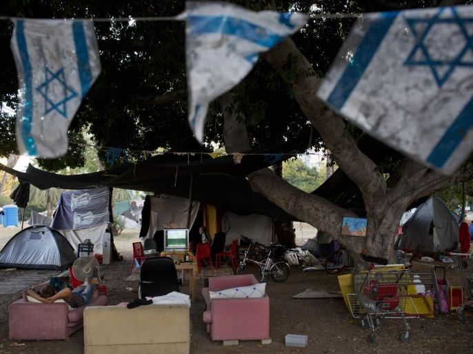 An Israeli homeless man sleeps on a sofa outside his tent where other homeless live for a couple of years, in a public park in the center of Tel Aviv, Israel, Tuesday, June 24, 2014. Israel on Tuesday joined an influential group of rich nations that help poor indebted economies, giving the country an international boost of recognition for its economic accomplishments. The news that Israel had been accepted into the Paris Club of creditor nations was welcomed by Israeli policy makers, who are facing calls to reduce high levels of poverty and inequality even as the country’s economy appears to be humming along. (AP Photo/Oded Balilty)
