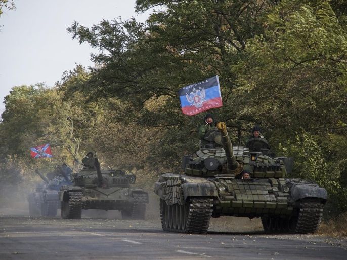 In this photo taken on Wednesday, Oct. 21, 2015, Russia-backed rebel tanks with a flag of the self-proclaimed Donetsk People's Republic, move to storage during the withdrawal of weapons near Novoazovsk, eastern Ukraine. The fighting has subsided, but Donetsk is quickly sinking into the past, a shabby Soviet-like state of empty streets and deprivation. Huge portraits of Josef Stalin hanging in the city center only reinforce the impression of failure. (AP Photo/Max Black)