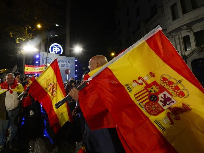 RR2137 - Madrid, -, SPAIN : Popular Party (PP) supporters wave Spanish flags in front of the party's headquarters after the partial results of Spain's general elections in Madrid on December 20, 2015. Spain's ruling conservative Popular Party won the most votes, 26.8 percent, in a general election today but lost its absolute majority in parliament, an exit poll showed. AFP PHOTO / JOSE JORDAN