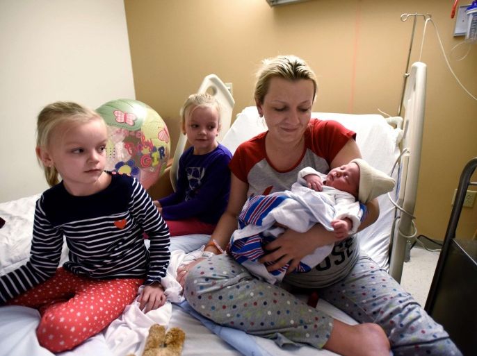 Magdalena Daniszewski, of Elmwood Park, holds her newborn daughter Kamila Daniszewski, the first local baby of 2016, as her twin sisters Linda, left, and Nina, right, watch at St. Joseph's Hospital in Paterson, N.J., Friday, Jan. 1, 2016. (Danielle Parhizkaran /The Record of Bergen County via AP) ONLINE OUT; MAGS OUT; TV OUT; INTERNET OUT; NO ARCHIVING; MANDATORY CREDIT