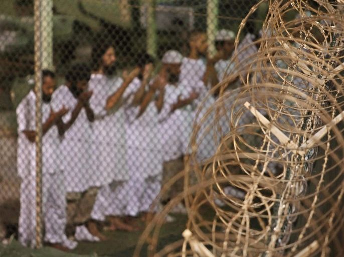FILE - In this May 14, 2009, file photo, reviewed by the U.S. military, Guantanamo detainees pray before dawn near a fence of razor-wire, inside Camp 4 detention facility at Guantanamo Bay U.S. Naval Base, Cuba. Ten prisoners from Yemen who were held at Guantanamo Bay, have been released and sent to the Middle Eastern nation of Oman for resettlement, U.S. Secretary of State Ash Carter said Thursday, Jan. 14, 2015. (AP Photo/Brennan Linsley, File)