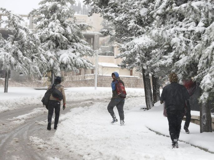 Syrian workers carry their belonging as they walk on the snow in Aley, Lebanon, January 1, 2016. REUTERS/ Jamal Saidi