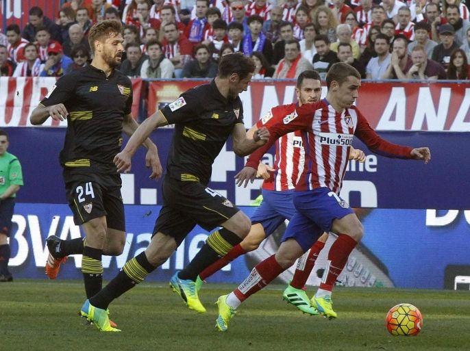 Atletico Madrid's French striker Antoine Griezmann (R) fights for the ball with Sevilla FC's players during their Primera Division soccer match played at Vicente Calderon stadium in Madrid, Spain on 24 January 2016.