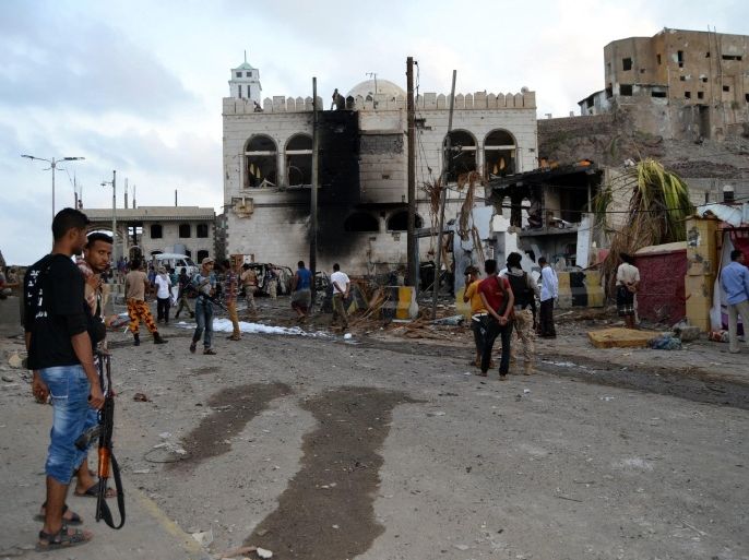 Armed Yemenis inspect the scene of a car bomb attack that apparently targeted the gate of Yemen's Presidential Palace in the country's temporary capital of Aden, Yemen, 28 January 2016. At least 12 people were killed 28 January in the bombing claimed by the Islamic State terrorist group near the presidential palace in Aden. The dead included security guards and civilians, security officials said.