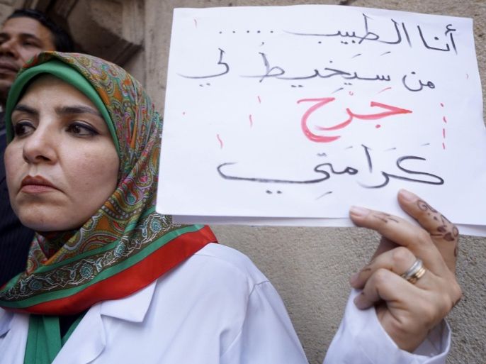 An Egyptian doctor holds an Arabic placard reading, "I'm the doctor, who will treat my dignity wound?" during a protest against rampant police abuses, after two doctors were beaten up by policemen in a Cairo hospital, in front of their headquarters of the Egyptian Medical Syndicate in Cairo, Egypt, Friday, Feb. 12, 2016. Doctors threatened to escalate if the government doesn’t hold police accountable for abuses. (AP Photo/Amr Nabil)