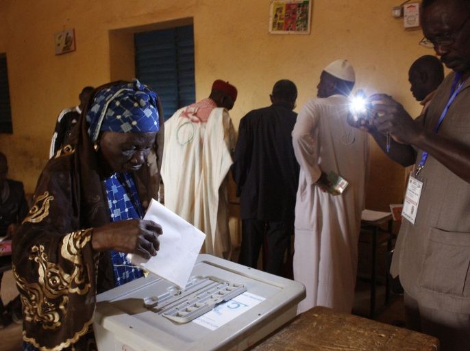 A woman cast's her ballot, as a official, right, takes a photos with his phone, during elections in Niamey, Niger, Sunday, Feb 21, 2016. Niger President Mahamadou Issoufou stood for re-election in the West African nation on Sunday, touting his record of defending the country from Islamic extremists as he vied against 14 other candidates for a second five-year term. (AP Photo/Gael Cogne)