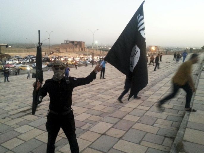 A fighter of the Islamic State of Iraq and the Levant (ISIL) holds an ISIL flag and a weapon on a street in the city of Mosul, Iraq, in this June 23, 2014 file photo. To match Special Report MIDEAST-CRISIS/IRAQ-ISLAMICSTATE REUTERS/Stringer/Files