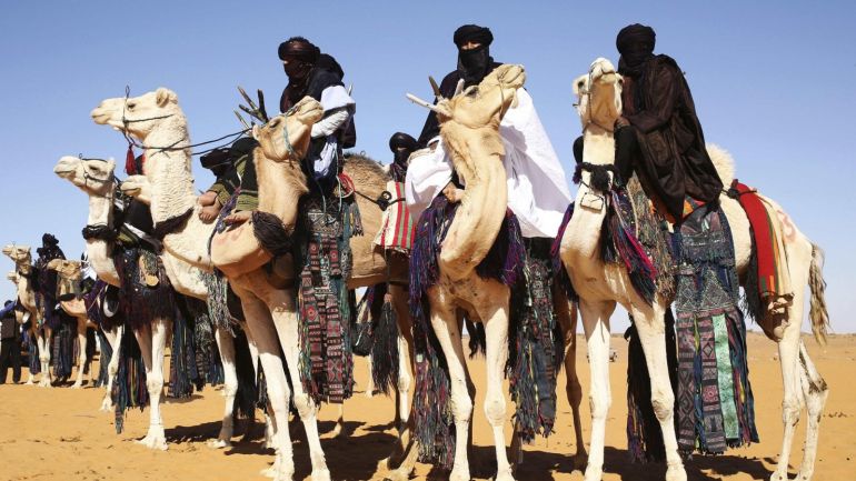 Tuareg men ride camels in the desert during the 19th Ghat Festival of Culture and Tourism, in Ghat, about 1,360 km (845 miles) south of Tripoli December 30, 2013. In the annual event, Tuareg tribes from the region and tourists meet to celebrate Tuareg traditional culture, folklore and heritage. Picture taken December 30, 2013. REUTERS/Esam Omran Al-Fetori (LIBYA - Tags: TRAVEL SOCIETY ANIMALS)