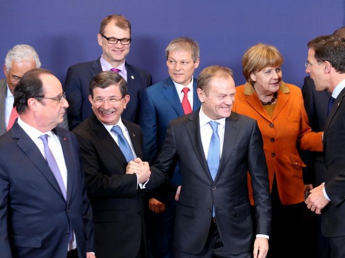 European Council President Donald Tusk, front center, shakes hands with Turkish Prime Minister Ahmet Davutoglu, front second left, during a group photo at an EU summit in Brussels on Monday, March 7, 2016. European Union leaders are holding a summit in Brussels on Monday with Turkey to discuss the current migration crisis. Other leaders left to right, Portuguese Prime Minister Antonio Costa, French President Francois Hollande, Finnish Prime Minister Juha Sipila, Romanian Prime Minister Dacian Ciolos, German Chancellor Angela Merkel, Dutch Prime Minister Mark Rutte and Slovenian Prime Minister Miro Cerar. (AP Photo/Francois Walshaerts)