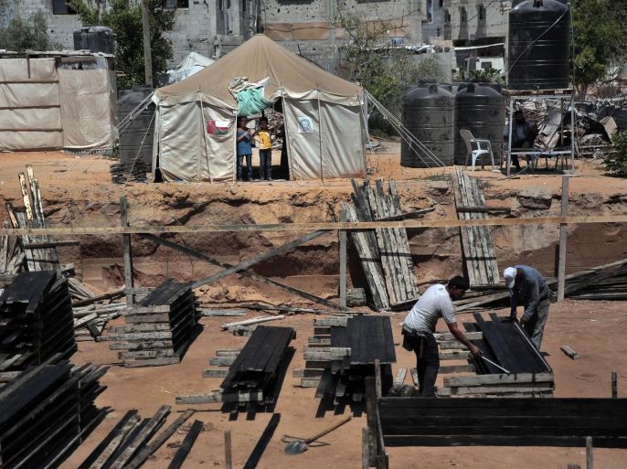 Two Palestinian boys stand outside a tent, background, watching workers rebuild a house which was destroyed during the last summer's war between Israel and Hamas, as the long-awaited reconstruction began in Shijaiyah neighborhood eastern Gaza City on Thursday, July 23, 2015. Construction has started on the first homes that will be rebuilt in the Gaza Strip since the devastating war destroyed much of the territory's infrastructure. (AP Photo/Khalil Hamra)