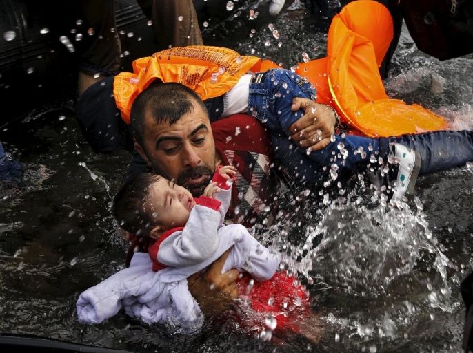 A Syrian refugee holds onto his children as he struggles to walk off a dinghy on the Greek island of Lesbos, after crossing a part of the Aegean Sea from Turkey to Lesbos September 24, 2015. Reuters and The New York Times shared the Pulitzer Prize for breaking news photography for images of the migrant crisis in Europe and the Middle East. REUTERS/Yannis Behrakis TPX IMAGES OF THE DAY