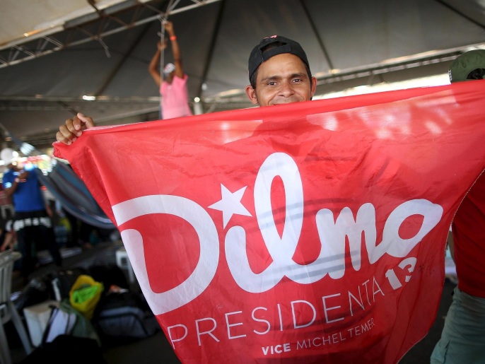 أحد أنصار روسيف يرفع لافتة مؤيدة لها وسط برازيليا(رويترز)