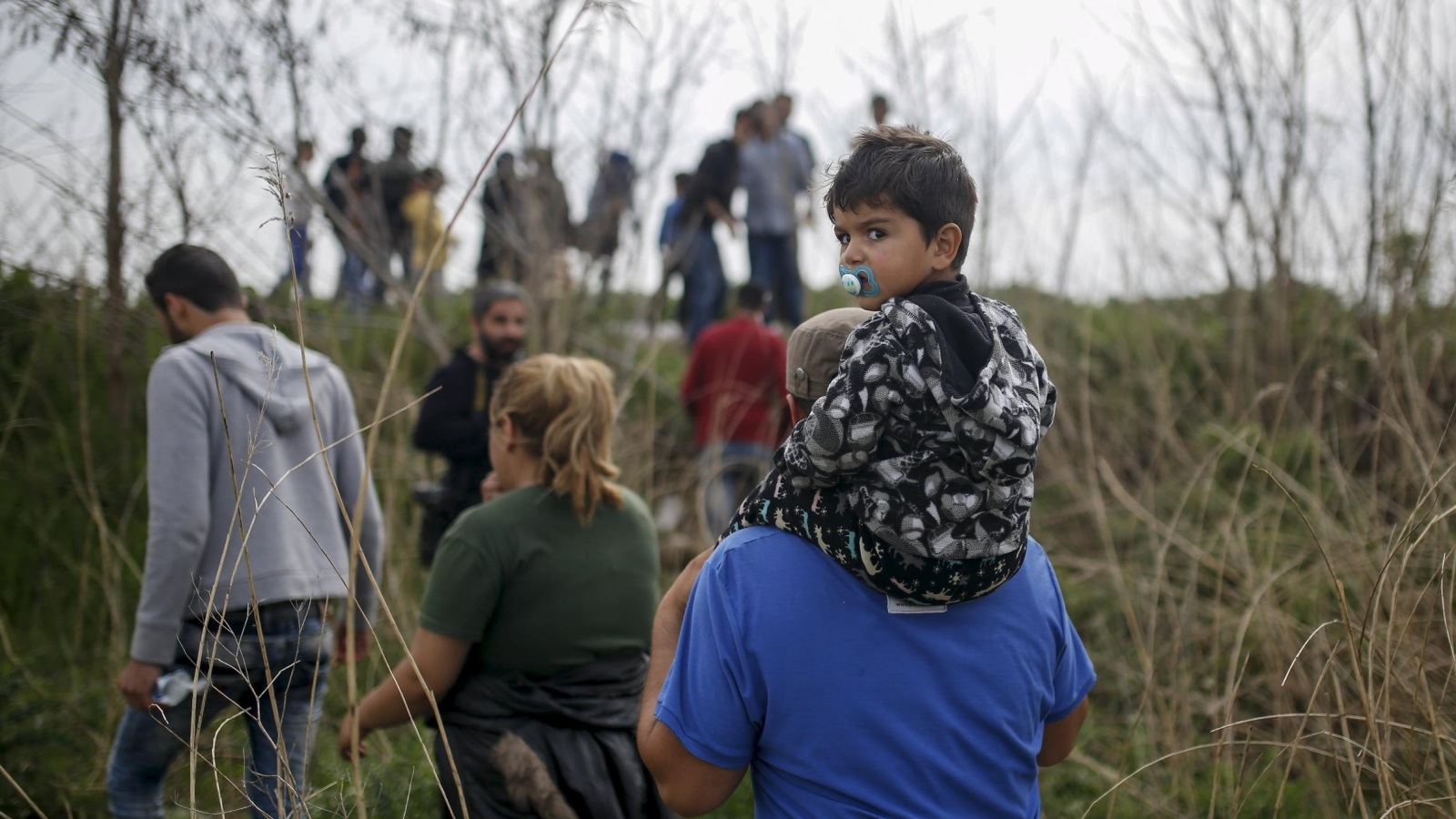 ‪لاجئون ومهاجرون قرب حدود اليونان مع مقدونيا‬ (رويترز)