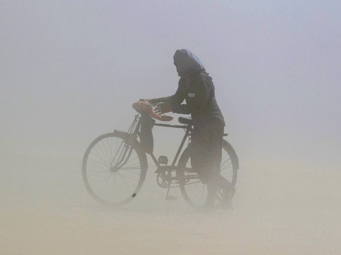 A man covers his face as he pushes a bicycle through a dust storm on the banks of the Ganga river in Allahabad, India, April 12, 2016 REUTERS/Jitendra Prakash TPX IMAGES OF THE DAY