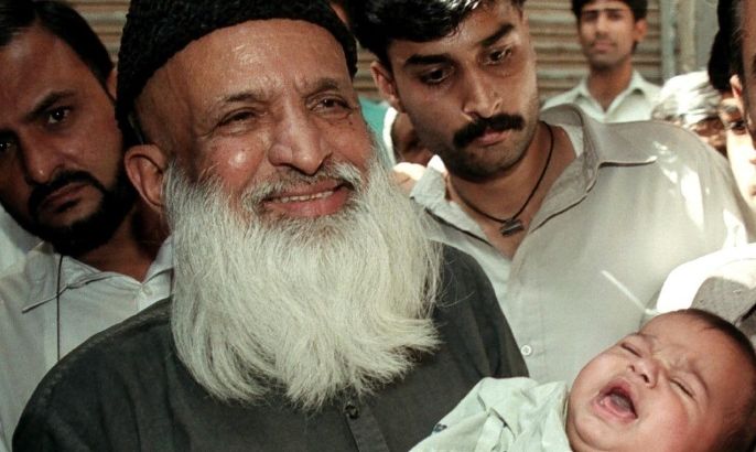 Renowned social worker Abdul Sattar Edhi holds a child handed over to him by local police in Karachi, Pakistan, March 15, 2002. REUTERS/Mohsin Hassan/File Photo
