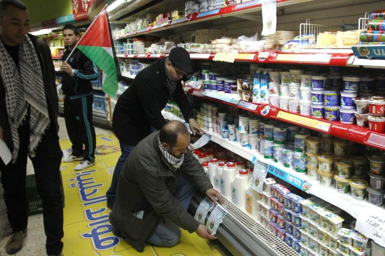 Palestinian activists stick leaflets calling for the boycott of Israeli products to a shelf selling Israeli dairy products in a supermarket in the West Bank town of Bethlehem on February 11, 2015. Data from Israel's Central Bureau of Statistics show that the Jewish state exports around $816 million worth of goods to the Palestinian Authority. AFP PHOTO / HAZEM BADER