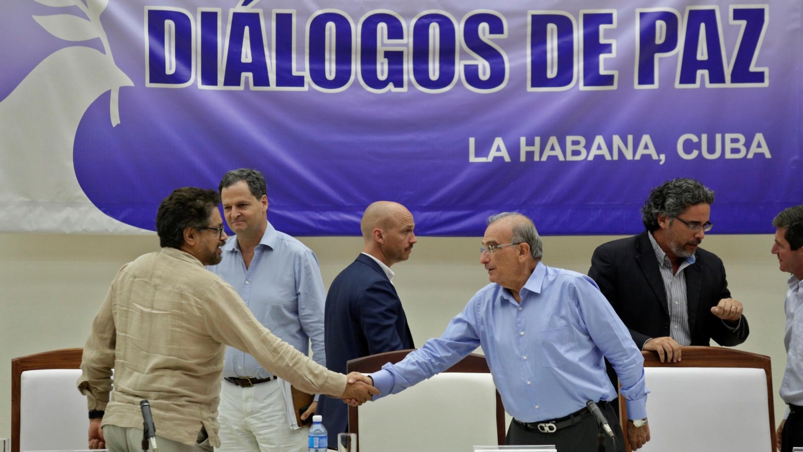 ممثلا الحكومة الكولومبية (يمين) وحركة فارك يتصافحان بعد توقيع بروتوكول اتفاق في هافانا (رويترز)