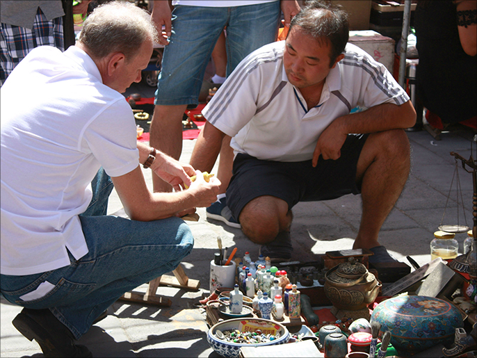 ‪زائر أجنبي يتفاوض مع أحد الباعة في سوق بان جيا يوان‬ (الجزيرة نت)