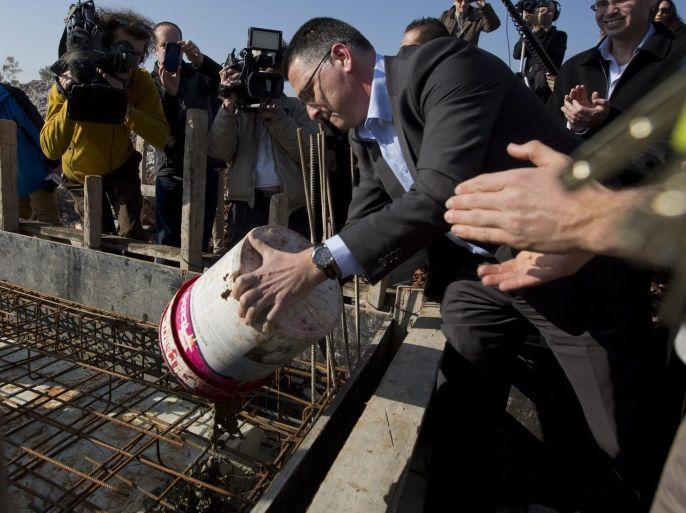 Israel's Interior Minister Gideon Sa'ar pours a bucket of cement on a building site as he begins a new neighborhood in the Jewish settlement of Gittit, in the Jordan Valley, 02 January 2014, amid much media attention. Israeli lawmakers toured the Jordan Valley today stressing its importance as US Secretary John Kerry arrives for another round of talks, amid speculation he might announce some 'framework' peace accords rather than the final status peace deal he annou
