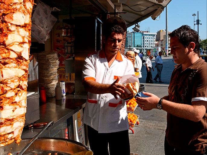 Turkish cook Ebubekir Bulus (L) (29) gives the doner sandwich to the customer (R) in front of the small traditional fast food shop in Istanbul, Turkey on 17 July 2007. Turkish authorities put some regulations for standardization of the Doner which is one of the most popular traditional fast food in Turkey. Doner can produce from chicken or cow meat. EPA/KERIM OKTEN