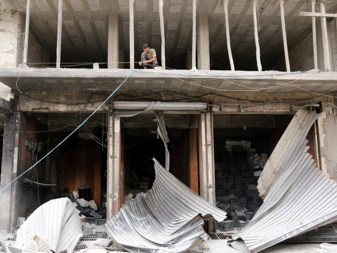‪سوري يحاول إصلاح أضرار فوق متاجر طالها القصف الجوي بحي القاطرجي شرقي حلب‬ (رويترز)