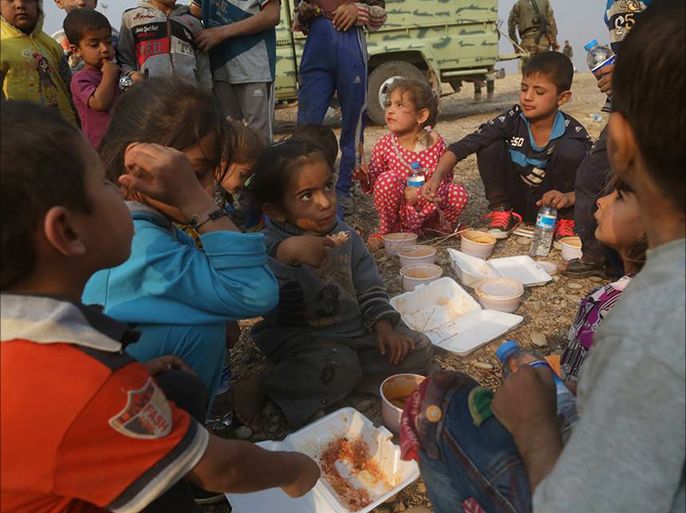 أطفال نازحون يأكلون طعاما يقدم لهم كمساعدات في المخيمات