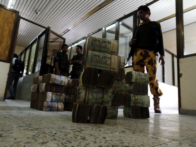 Houthi militiamen stand next to money donated by Yemeni to the Houthi rebels-held Central Bank of Yemen, in Sana'a, Yemen, 27 September 2016. According to reports, the Houthi rebel leader Abdul-Malik al-Houthi has pleaded for financial support from Yemenis after the Saudi-backed Yemeni Government relocated the central bank from the rebel-held Sana'a to the southern port city of Aden, accusing the Houthis of draining the bank's reserves to fund their militiamen.