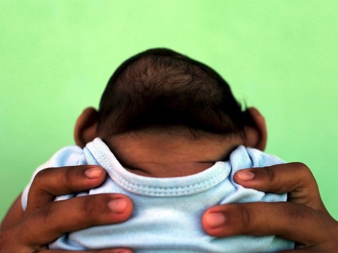 Jackeline, 26, holds her son who is 4-months old and born with microcephaly, in front of their house in Olinda, near Recife, Brazil, in this February 11, 2016 file photo. Evidence is building for the theory that Zika can cause newborn brain defects, and the World Health Organization is promising more answers in weeks, but nailing a definitive link will be neither simple nor swift. Picking apart numerous potential connections between mothers who show evidence of infection with the mosquito-borne virus and babies born with microcephaly, in which the head is abnormally small, will require precision and patience, specialists say. To match Insight HEALTH-ZIKA/MICROCEPHALY REUTERS/Nacho Doce/Files