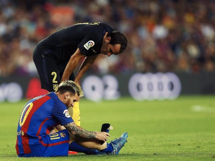 Atletico Madrid's Diego Godin next to FC Barcelona's Lionel Messi sitting on the turf after he picked up an injury during the Spanish Primera Division soccer match between Barcelona and Atletico Madrid at Camp Nou in Barcelona, Spain, 21 September 2016.