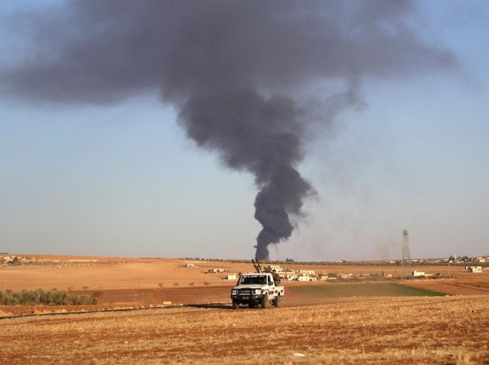 Rebel fighters ride a military vehicle near rising smoke from al-Bab city, northern Aleppo province, Syria October 26, 2016. REUTERS/Khalil Ashawi