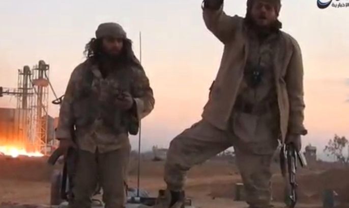 A still image taken from a video released by Islamic State-affiliated Amaq news agency, said to be in Palmyra, on December 11, 2016, purports to show Islamic State fighters in front of silos on fire and said to have been taken over by them. Handout via REUTERS TV ATTENTION EDITORS - THIS IMAGE WAS PROVIDED BY A THIRD PARTY. EDITORIAL USE ONLY. NO RESALES. NO ARCHIVE. REUTERS IS UNABLE TO INDEPENDENTLY VERIFY THIS IMAGE