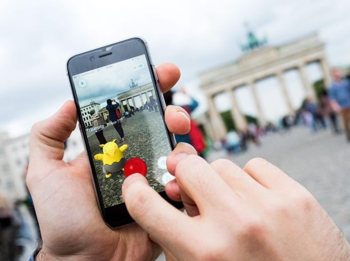 A picture made available on 14 July 2016 shows man trying to catch a pokemon called 'Drowzee' with a pokeball using the 'Pokemon Go' augmented reality mobile phone app in front of the Brandenburg Gate in Berlin, Germany, 13 July 2016. The app has been available in German app stores since 13 July. The app allows users to collect pokemon and battle against each other.