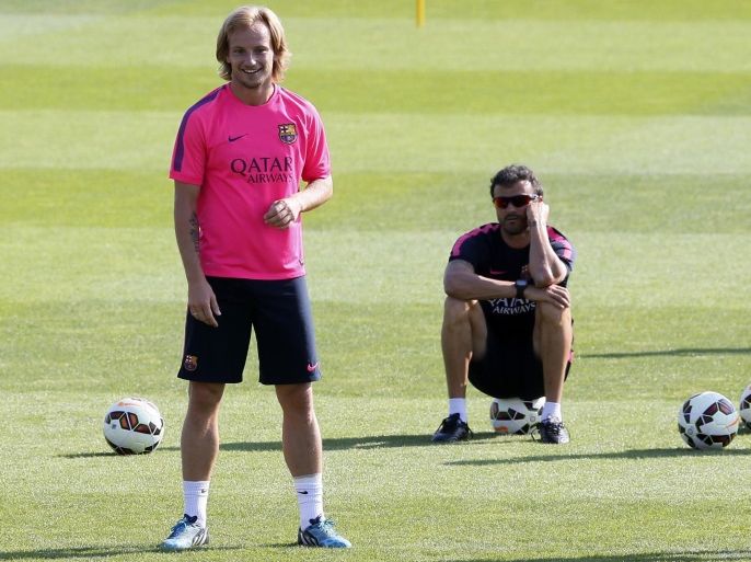 FC Barcelona's coach Luis Enrique (R) sits on a ball while Ivan Rakitic takes part in a training session at Joan Gamper training camp, near Barcelona August 5, 2014. REUTERS/Albert Gea (SPAIN - Tags: SPORT SOCCER)